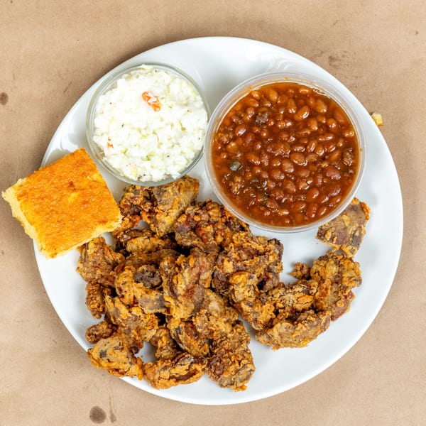 Fried chicken livers, baked beans, coleslaw, and cornbread on a white plate.